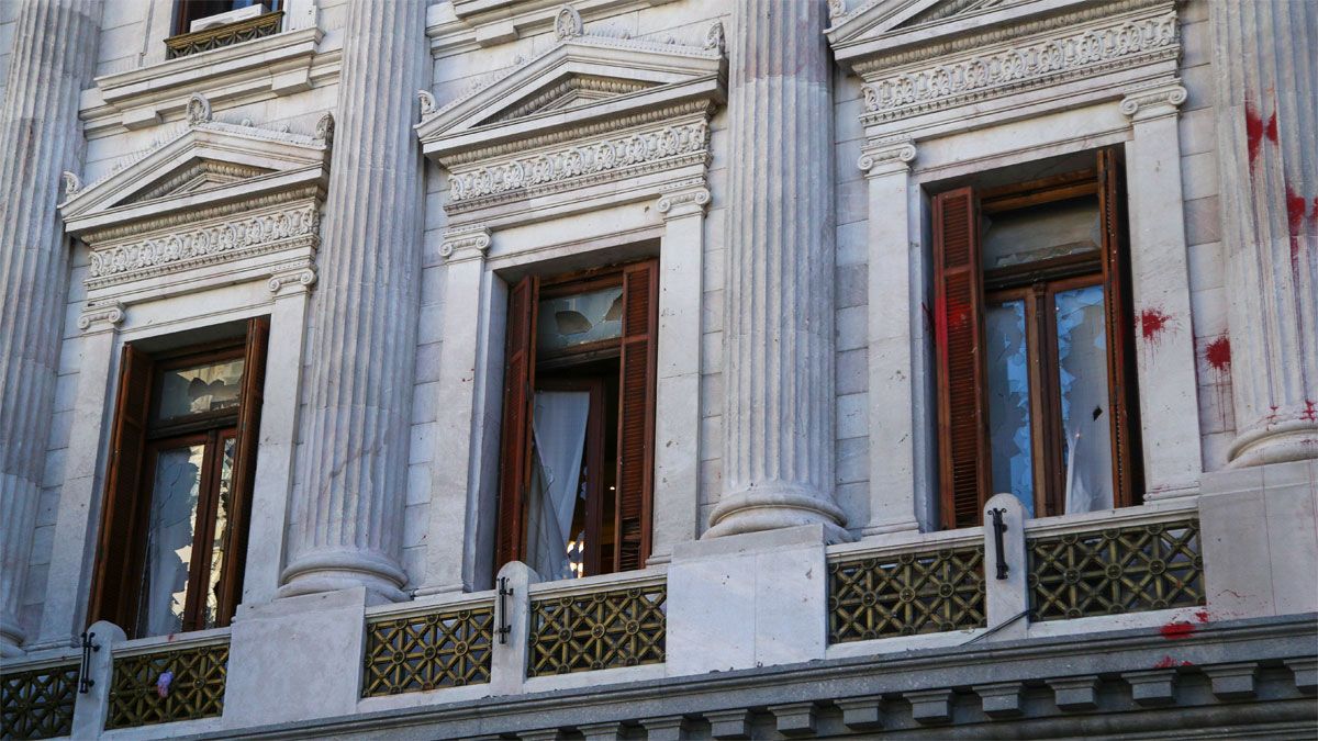 En ventanas de despachos del Senado que dan a la avenida Entre Ríos se observan manchas de pintura y vidrios rotos producto de las piedras que arrojaron manifestantes mientras los legisladores debaten el acuerdo con el FMI en el interior del recinto.