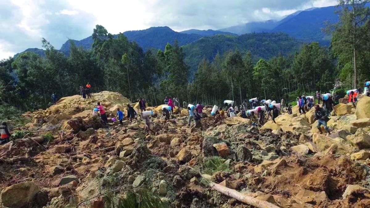 Personas cargan bolsasdespués de un deslizamiento de tierra ocurrido este viernes en la provincia deEnga
