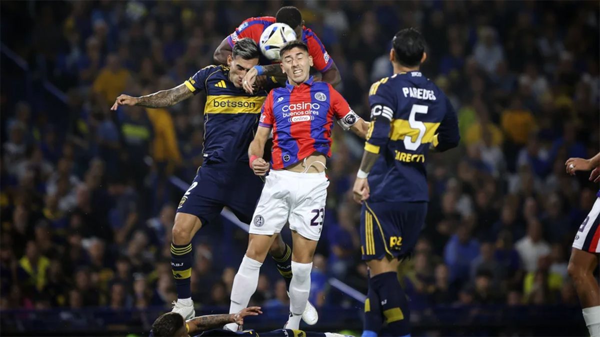 El colombiano Romaña cabecea la pelota ante la presencia de su compañero Gastón Hernández y el rival Lautaro Di Lollo.