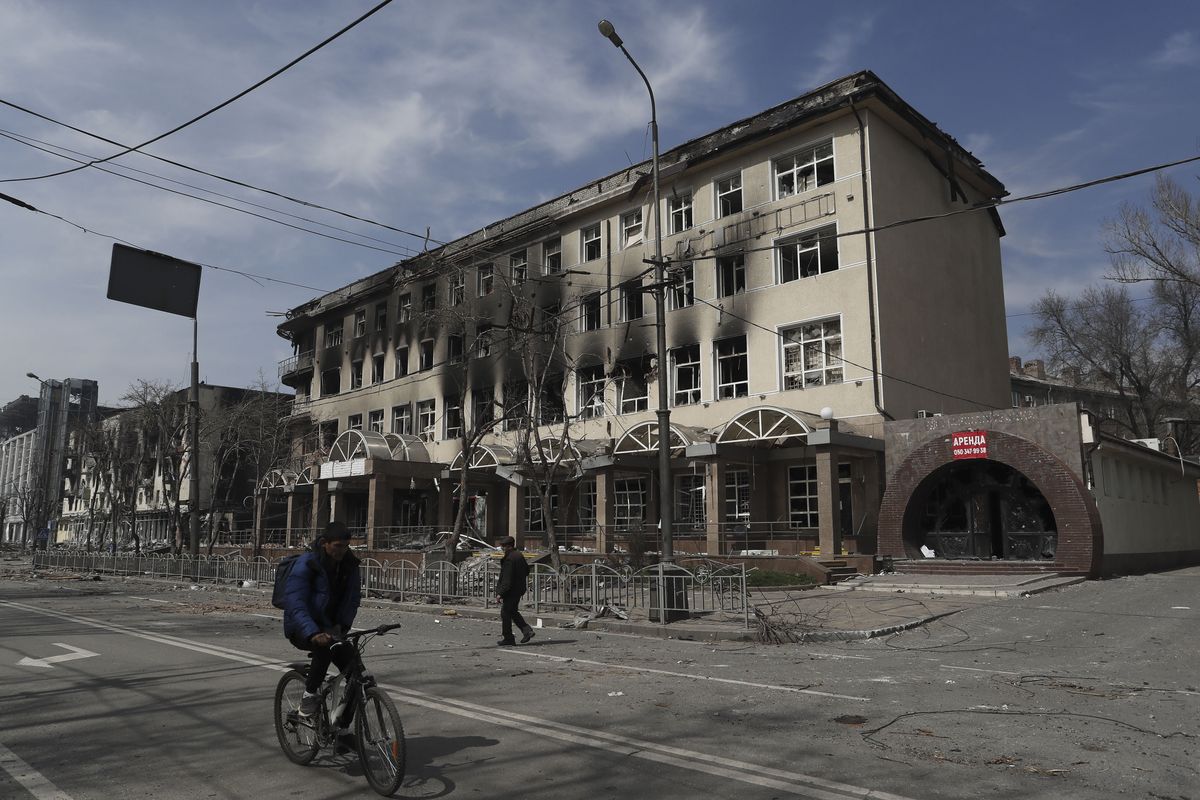 Algunos de los pocos residentes que quedaron en la ciudad de Mariúpol pasan cerca de un edificio dañado por los ataques rusos.