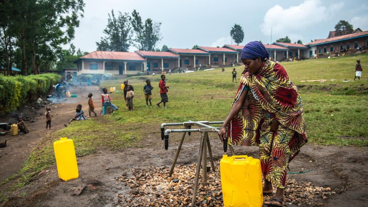 Una mujer que huyó de su hogar al estallar el conflicto en una aldea de la provincia de Kivu del Norte (República Democrática del Congo) recoge agua frente a una escuela provincial. Foto Unicef.