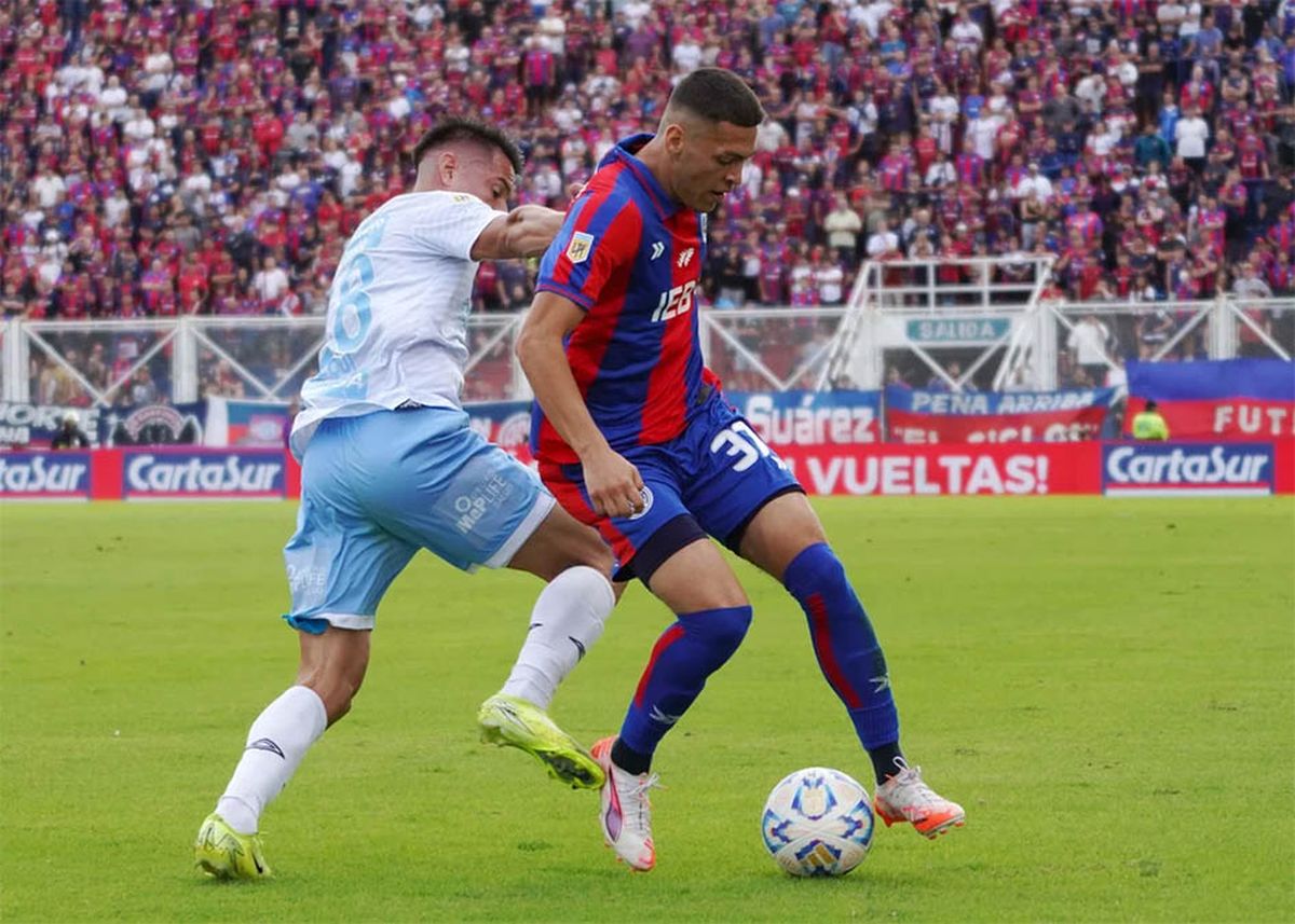 Elías Báez cuida la pelota ante la marca insesante de Carlos Auzqui.